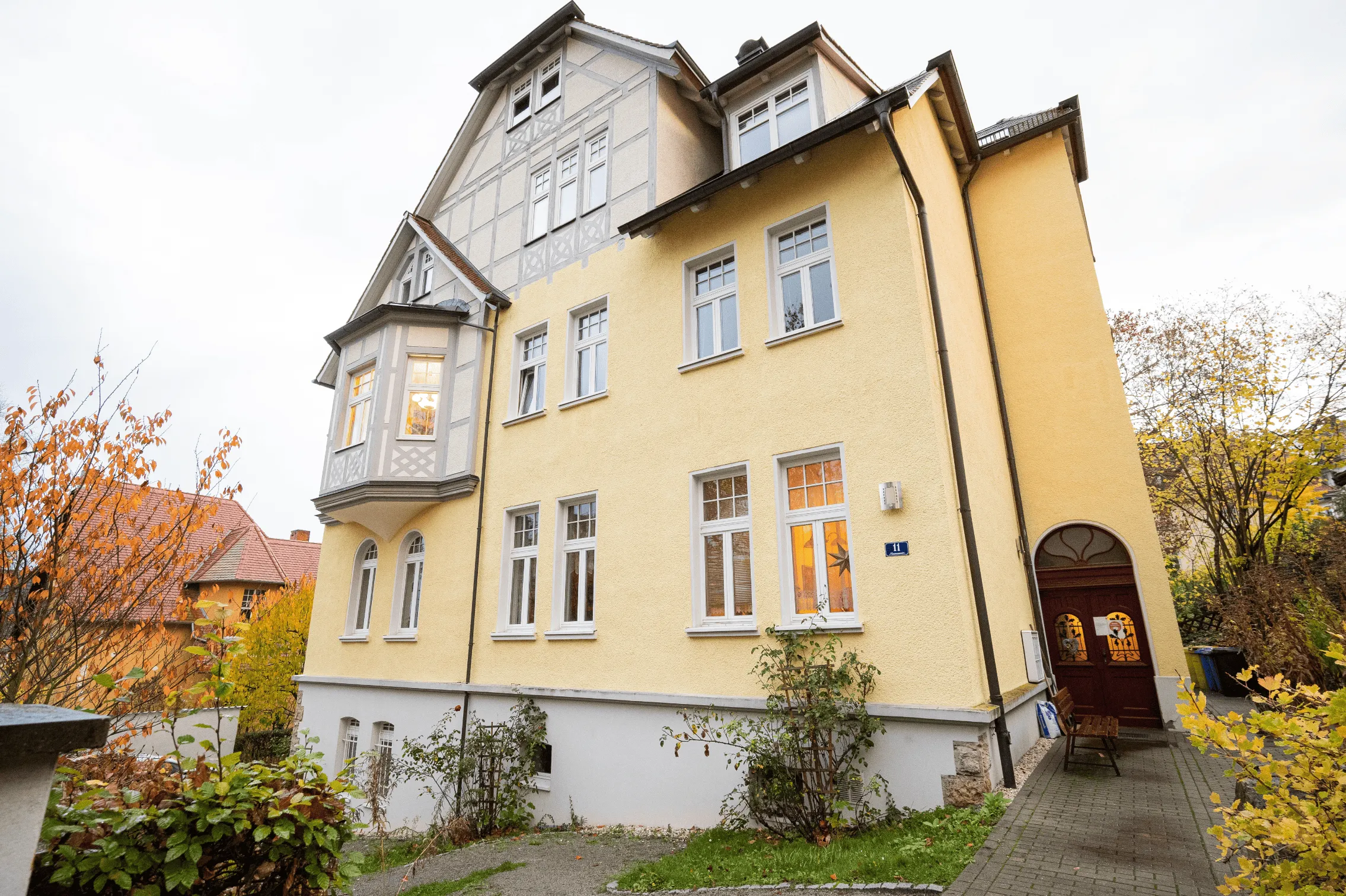 Gelbes Altbauhaus mit Fachwerkgiebel und Erker im Herbst, Wohnstandort von Silenza Pflege in Jena